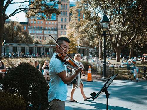 human man playing violin at the park people
