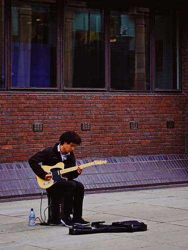 human man playing with his electric guitar while sitting on guitar amlplifier people
