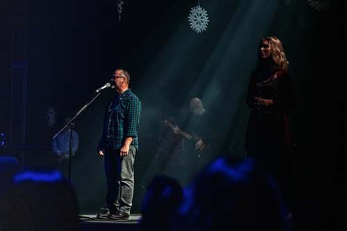 human man singing in front of a microphone in the stage guitar
