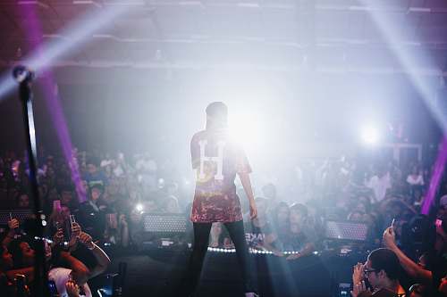 human man singing on stage in front of crowd people