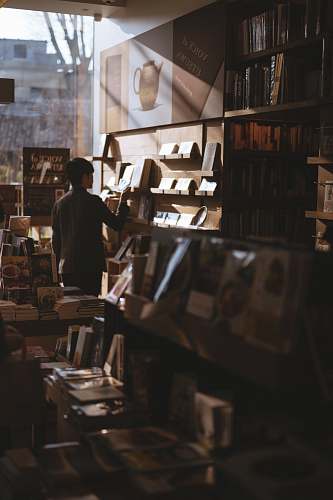 human man standing inside library finding books people