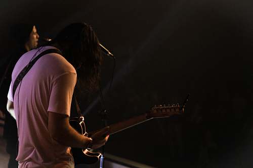 human man standing while playing guitar people