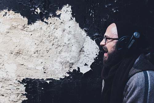 human man using headphones shouting beside wall sing