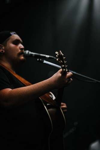 human person playing guitar while singing people