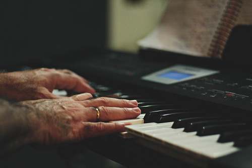 human shallow focus photo of person playing piano keyboard