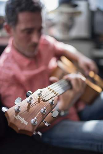human shallow focus photography of man playing guitar people