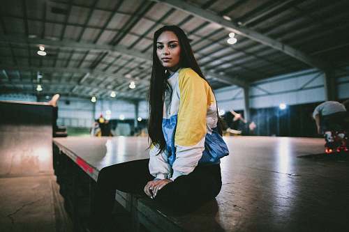human sitting woman wearing yellow, white, and black jacket people