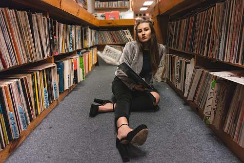 human woman sitting on floor between bookshelves people