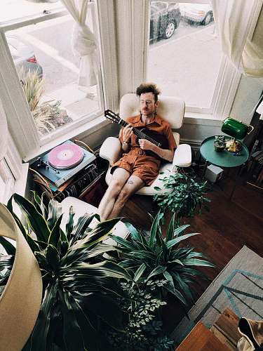 flora man sitting on sofa chair playing classic guitar jar