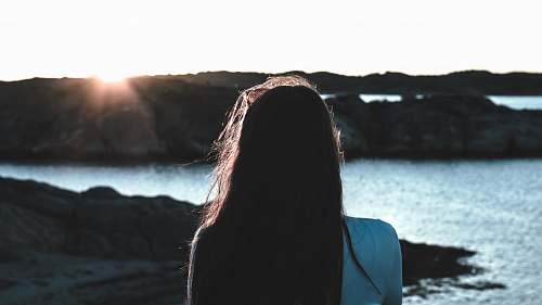 ocean photo of woman in white shirt near body of water water