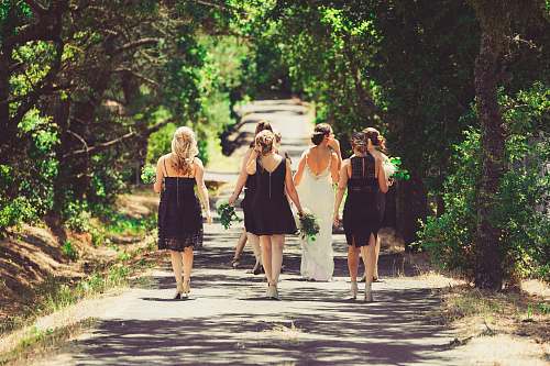 human bride and bridesmaid walking on street between green trees wedding