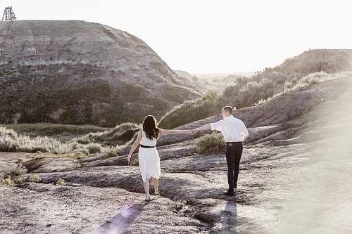 person couple holding hands while walking along the rocky coastline couple