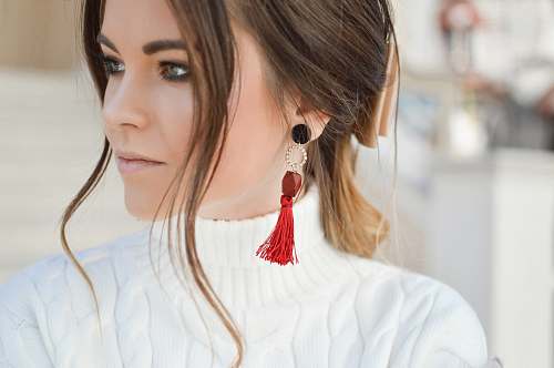person focus photography of woman wearing red tassel earrings while looking on her left side human
