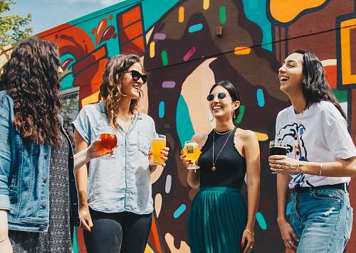 person four women holding drinks while laughing together during daytime human