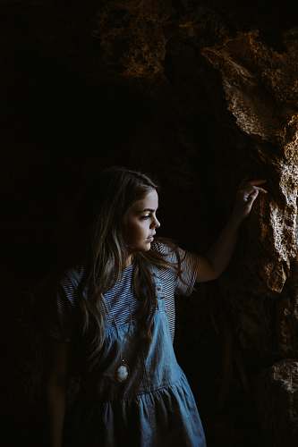 girl girl wearing blue and white dress holding on brown rocks cave