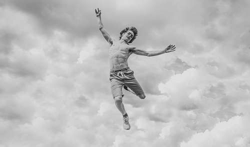 person grayscale photo of person jumping overlooking clouds black-and-white