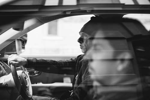 human grayscale photo of two men riding on vehicle black-and-white