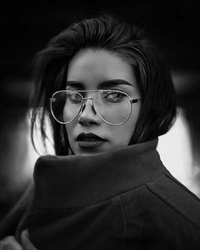 black-and-white grayscale photo of woman wearing coat and eyeglasses portrait
