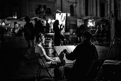 human grayscale photography of people at the street near buildings during night black-and-white