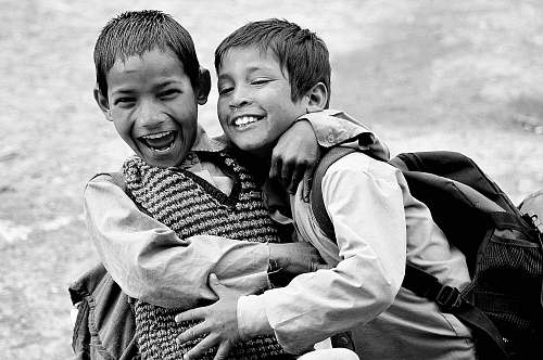 human grayscale photography of two boys hugging while laughing black-and-white
