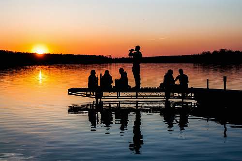 silhouette group of people on wooden dock during sunset in silhouette photography dock
