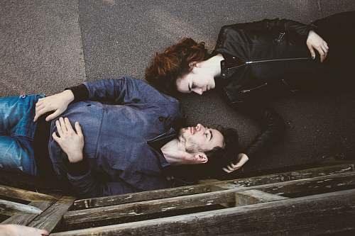 couple man and woman lying on gray concrete surface looking at each other love