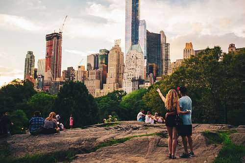 person man and woman standing on hill looking at s skyscraper human