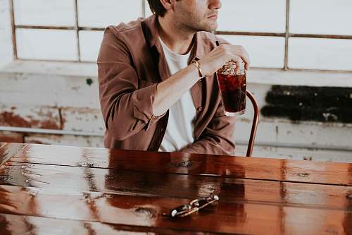 human man holding drinking glass beside the table person