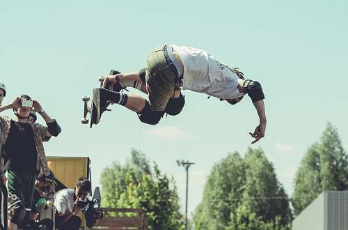 person man holding skateboard while doing tricks during daytime human