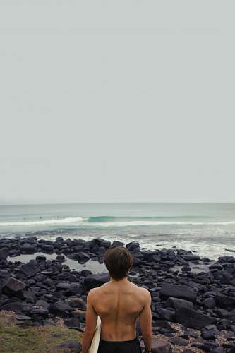 person man holding surfboard near sea back