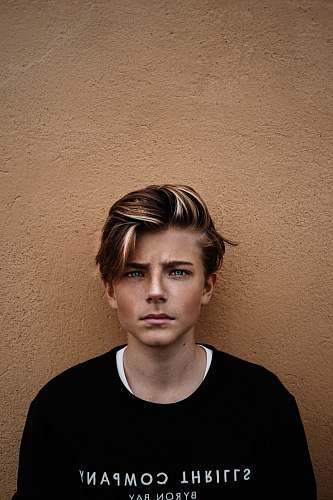 human man in black crew-neck shirt near brown wall person