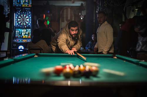 person man in brown jacket playing billiard table