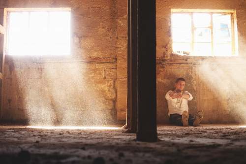 person man sitting beside concrete wall human