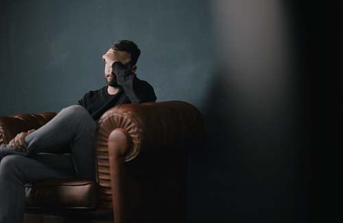 human man sitting on sofa against wall couch