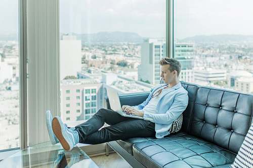 couch man sitting on sofa while using laptop furniture