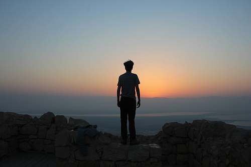 person man standing on white stones looking in sea human
