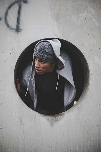 person man wearing black shirt and knit cap with hoodie jacket inside concrete hole human