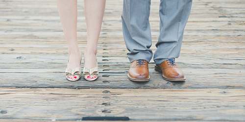 person man wearing brown leather oxford shoes beside woman wearing gold open-toe sandals shoes