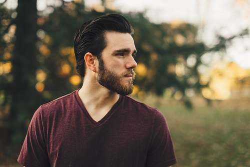 person man wearing maroon V-neck t-shirt in forest human