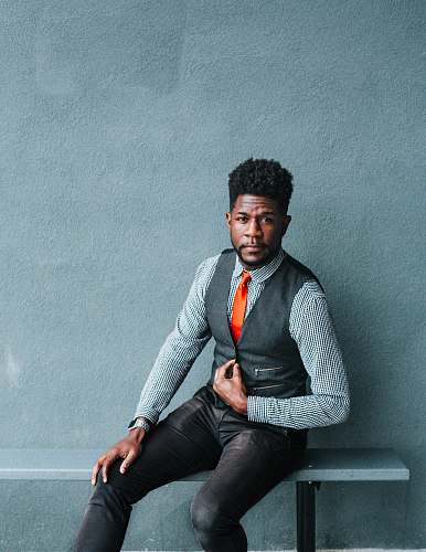 person man wearing vest sitting on bench human