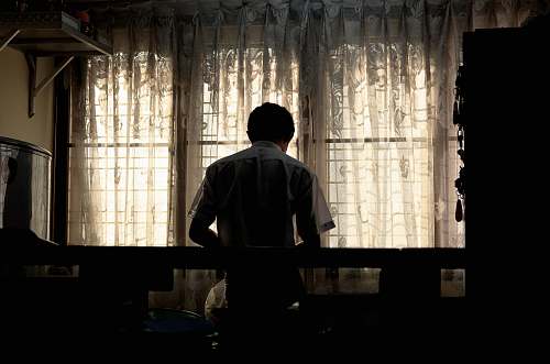 person man wearing white collared shirt near window curtain