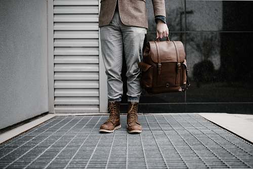 boot person holding brown leather bag bag