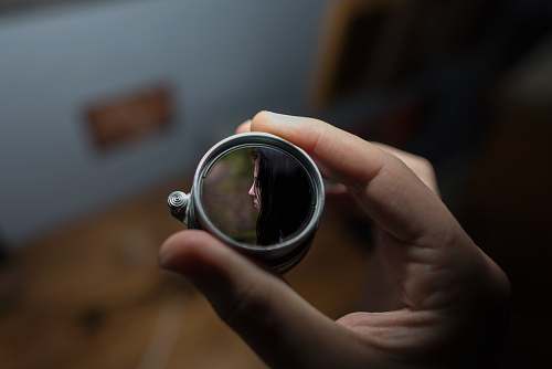 person person holding round grey mirror selective focus photography human