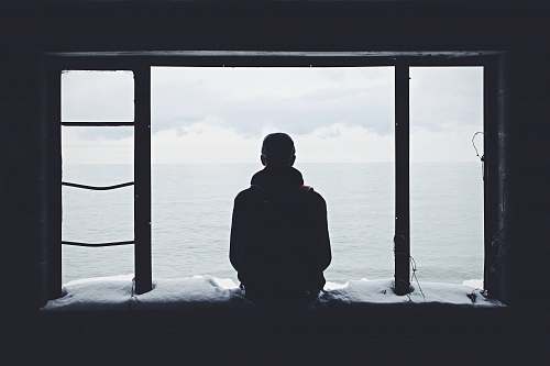 person person looking out through window silhouette