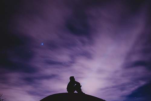 person person sitting on black surface looking to sky silhouette