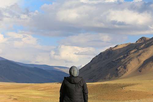 person person standing in front of brown mountain nature