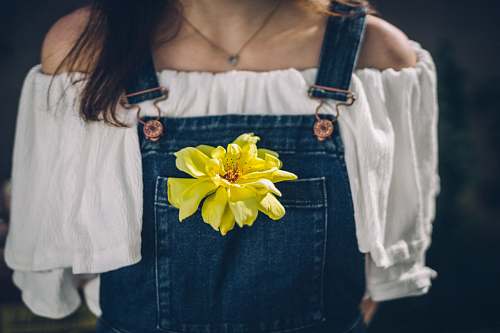 person person wearing overalls with yellow petaled flowers on pocket jeans