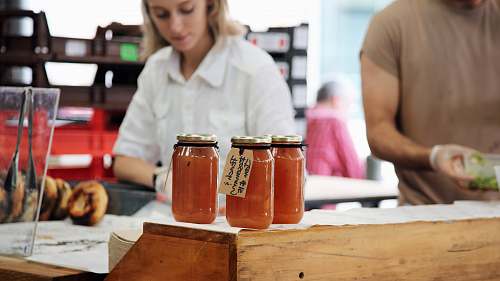 person photo of three clear glass mason jars jam