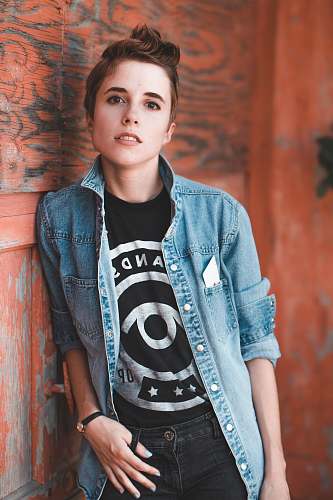 person portrait photography of woman leaning beside on brown wooden wall human