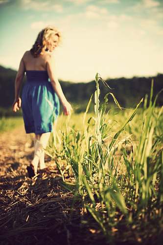 woman selective focus photo of woman wearing blue dress standing on grass field field